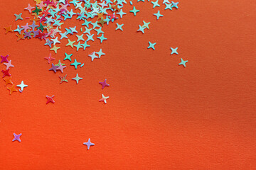 Shiny bright colorful glitter on orange background. Space for text