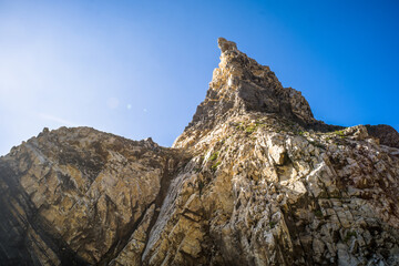 Cliffs, sharp spectacular rocks rising from the ocean. waves. Ursa sandy beach under the cliff. Sunny day. Horizontally