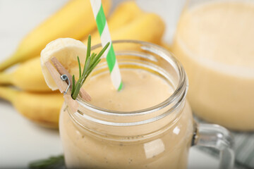 Obraz na płótnie Canvas Mason jar of tasty banana smoothie with straw, closeup