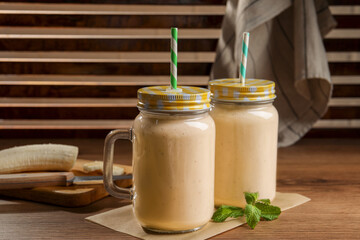 Tasty banana smoothie and mint on wooden table