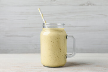 Mason jar with delicious fruit smoothie on white wooden table