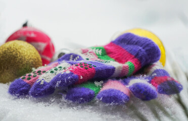 Gloves and Christmas tree toys in the white snow