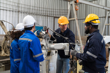 Group of engineer workers discuss and working, checking, repair, maintenance automatic welding robot arm machine at production line in the industry factory