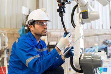 Male engineers worker holding digital tablet working with welding robot arm in workshop. Male...