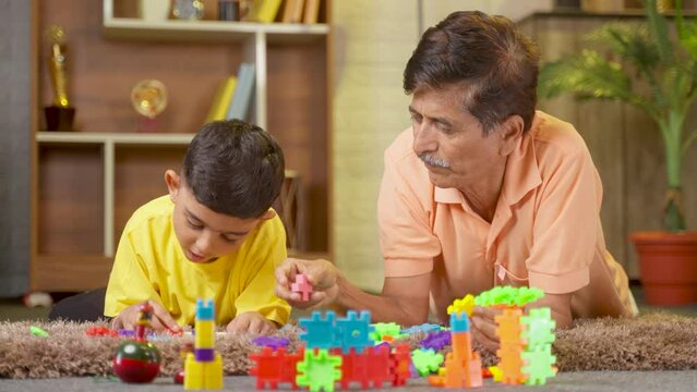 Happy Smiling Grandfather And Grandson Playing With Toys On Floor At Home - Concept Of Entertainment, Retirement Lifestyle And Family Bonding.