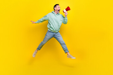 Fototapeta na wymiar Full length photo of excited impressed man wear sweatshirt making toa announcement empty space jumping high isolated yellow color background