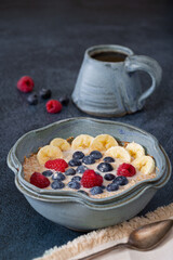 Plant based breakfast of steel cut oats and fruit with coffee on a dark blue surface with copy space