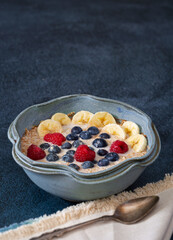 Bowl of organic steel cut oats topped with banana and berries mixed with almond milk; copy space