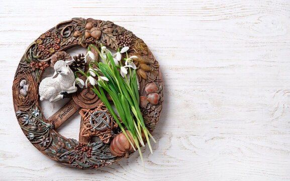 Wiccan altar for Imbolc sabbat. pagan festive ritual. Brigid's cross amulet, wheel of the year, snowdrop flowers, toy lamb on wooden table. Imbolc holiday, spring equinox. top view. copy space
