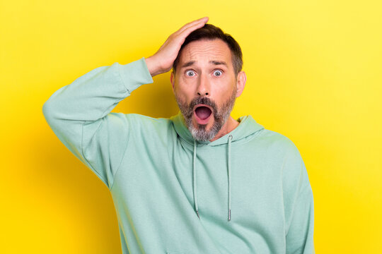 Photo of astonished speechless upset guy dressed mint sweatshirt hold palm on head forgot about sale isolated on yellow color background