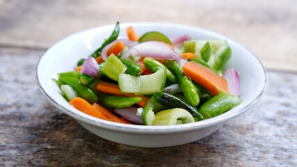 Acar timun, Indonesian traditional pickle cucumber. Side Dish for Chicken, Meat, or Martabak Dish. Diced Carrot and Cucumber with Green Chilli and Shallot, Mix with Vinegar, Sugar, Salt. On White Bowl