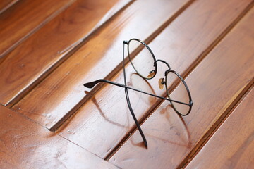 a close up of eyeglasses with black frames isolated natural patterned wooden background.