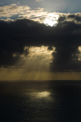 beautiful sunset over sea with sun rays between black clouds