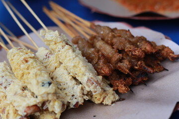 photo of chicken satay coated with fried egg and chicken intestine satay served with red chili sauce. Indonesian food called Sate Taichan. Food concept photo.