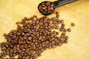 Dark roasted Arabica coffee beans on wooden table with tamper,coffee roasting concept