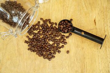 Dark roasted Arabica coffee beans on wooden table with tamper,coffee roasting concept