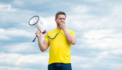 man in yellow shirt shout in loudspeaker on sky background