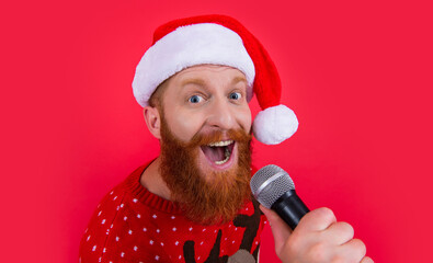 Portrait of Santa Claus singer studio isolated on red. Bearded man in Santa hat singing with mic