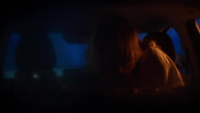 Mid 20s Caucasian couple passionately kissing on a backseat of a car