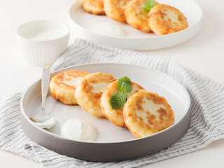 Cottage cheese pancakes, syrniki, on a light background. Copy space.