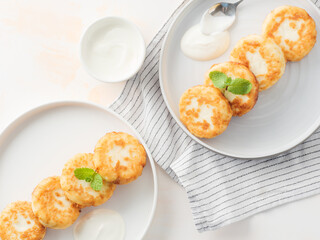 Cottage cheese pancakes, syrniki, on a light background. Copy space.