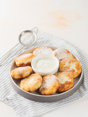 Cottage cheese pancakes, syrniki, on a light background. Copy space.