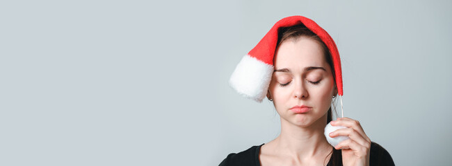 Portrait of beautiful woman with closed eyes in Santa Claus hat. Girl no has an idea. Unhappy, boring, tired and depressive person. Bad emotions on face. The end. Humor. Failure grimace. Without mood