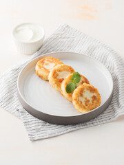 Cottage cheese pancakes, syrniki, on a light background. Copy space.
