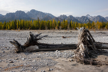Dried up river bed in a rural countryside with the snowy mountains in the background. Majestic landscape with the rock road and hills.