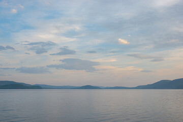 Majestic view of lake Khövsgöl, beautiful mountains in the background. Water coast with the misty looking sky with the clouds in horizon.