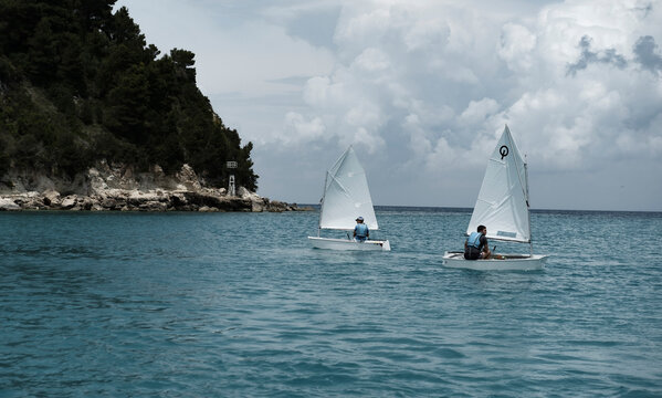 Greek Islands, Greece : 29 May 2022 : optimist sailing team on training in the sea close to coast , sailing sport activity, teenager outdoors