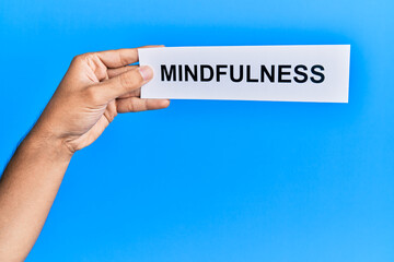 Hand of caucasian man holding paper with mindfulness word over isolated blue background