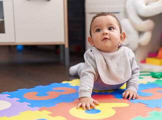Adorable hispanic baby crawling on floor at kindergarten