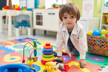 Adorable toddler playing with truck toy sitting on floor at kindergarten