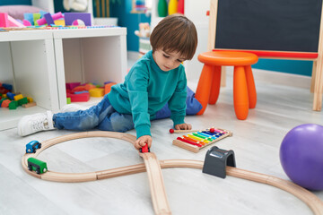 Adorable toddler playing with cars toy sitting on floor at kindergarten