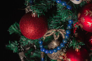 Red Christmas ball on a Christmas tree with a garland on the black background