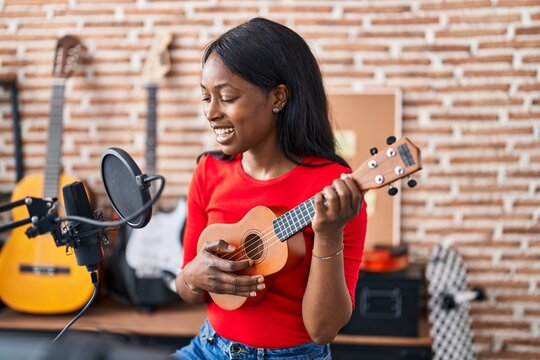 Young african american woman musician playing ukelele at music studio