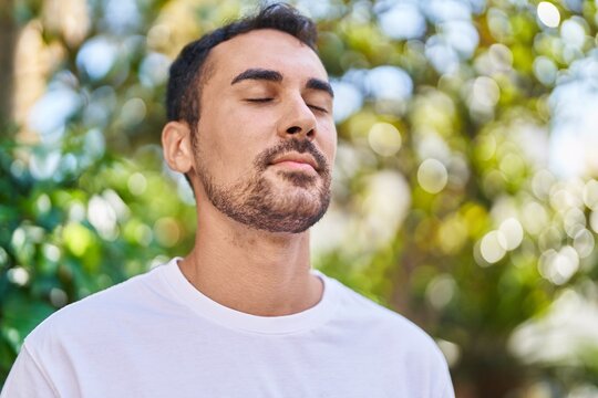 Young hispanic man breathing with closed eyes at park