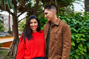Naklejka premium Man and woman couple smiling confident hugging each other at park