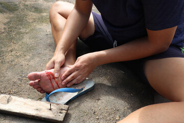 An Asian man shows a foot wound after stepping on a rusty nail on a wood. The wound from the foot...