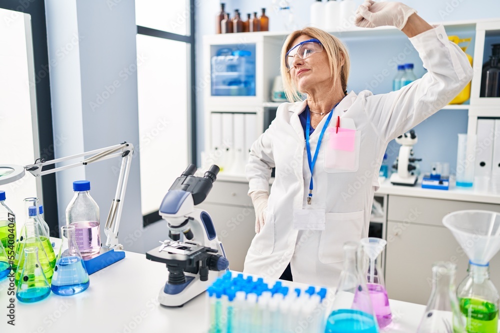 Wall mural Middle age blonde woman working at scientist laboratory stretching back, tired and relaxed, sleepy and yawning for early morning