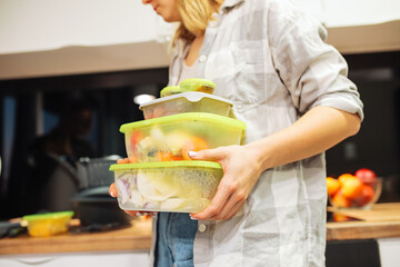 Unrecognizable women prepare food in stack of plastic containers in reserve in the kitchen. Food charity and donation
