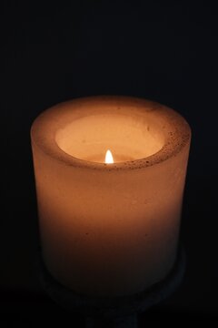 Brennende Kerze vor dunklem Hintergrund