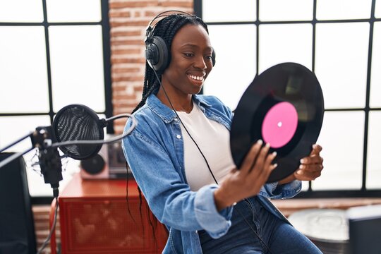 African american woman artist  smiling confident holding vinyl disc at music studio