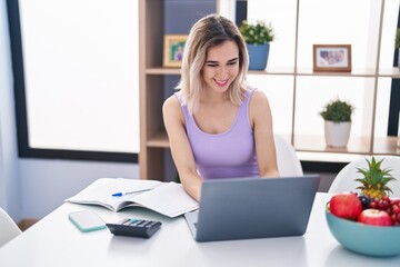 Obraz premium Young woman sitting on table teleworking at home