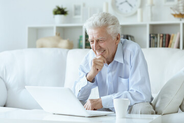 Fototapeta premium old nice man using laptop at home