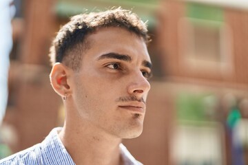 Young hispanic man with relaxed expression standing at street