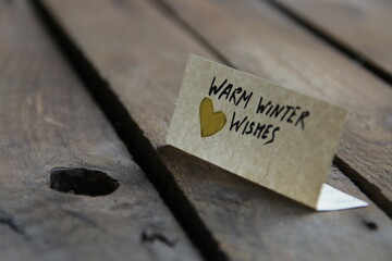 Warm winter wishes. The inscription on the tag on a wooden background.