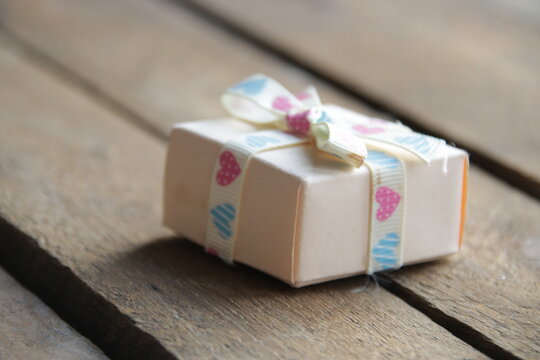 Gift with a ribbon on a beautiful wooden background.