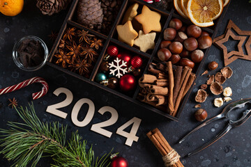 On the table there is a box with nine compartments in which nuts, cookies and spices are poured. On top are the numbers 2024